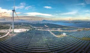 Home Panoramic aerial view of a renewable energy farm with solar panels and wind turbines in Vietnam at sunset.